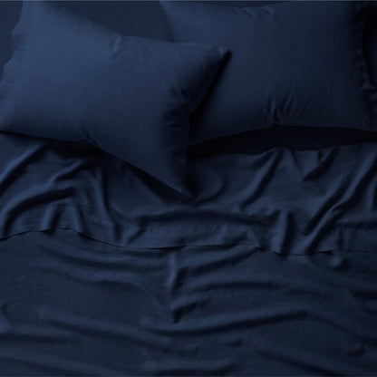 Tuft and Needle midnight sheet set on a mattress and 2 pillows on top.