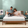 Man and woman laying on a Tuft & Needle Original mattress sitting in a brown bedframe